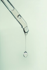 A drop of cosmetic oil falls from the pipette