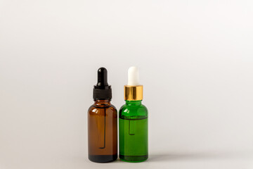 Amber and green glass serum bottles with dropper on white background. Assortment of unbranded products for face and body care. Copy space