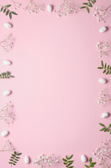Eggs, gypsophila and green twigs on a pink background. Frame. Easter concept