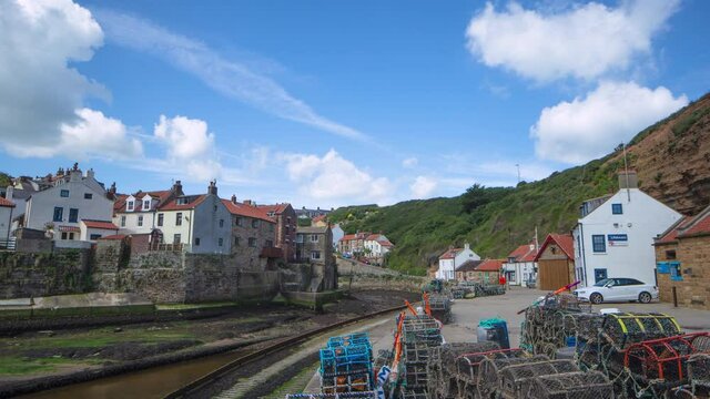 Staithes harbourside timelapse in summer with scudding clouds and bright sun. Taken from lower Cowbar, North Yorkshire Heritage Coast