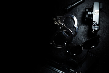 Black gun, flashlight, glasses, camera and Police metal real handcuffs lie on the black background. Private detective work. Searching information. Crime and robbery, prison concept.