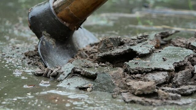 Close up shot of rural male Asian farmer digging the soil with a hoe to prepare for planting in rainy day.