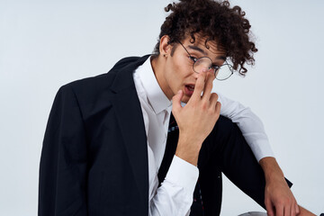 fashionable guy in classic suit and glasses sitting on the floor in a bright room cropped view