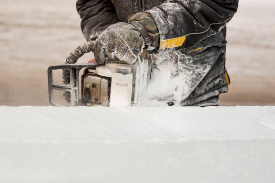 The sculptor cuts a figure from an ice block with a gasoline saw