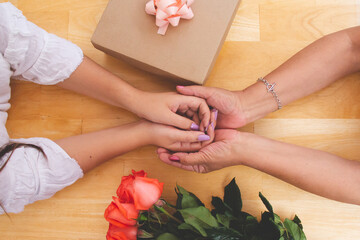 Joyful women spending time together. Lovely mother and her daughters having a great time. Mother's day concept. Women celebrating mother's day with their mom giving to her present and flowers.