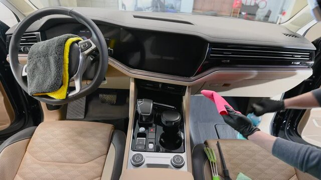 A man cleaning car interior with microfiber, car detailing and valeting concept.