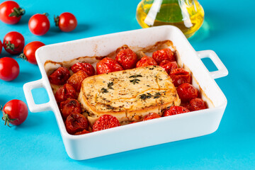 Trending viral Feta bake pasta recipe made of tomatoes, cheese, garlic and herbs in a casserole dish on a colored background.