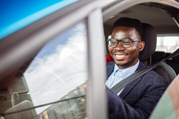 Man looking at mobile phone while driving. Portrait of a man using his cell phone while driving. Young man using his smartphone behind the wheel.