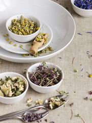 Assortment of dry herbs: chamomile, apple tree flowers, cornflower, lavender, thyme on rustic linen texture, closeup, natural medicine, naturopathy, homeopathy, making tea blends concept