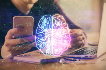 Double exposure of man's hand holding and using a digital device and brain hologram drawing. Data...