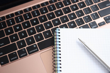 Spiral notepad and ballpoint pen lying on laptop keyboard closeup