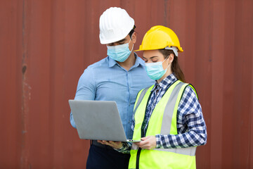 Technical expert in solar photovoltaic panels holding light bulb in hand and discussion with engineer woman in new project. Engineer wearing hygienic mask and protective hard hat.