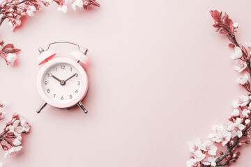 Spring time background. May flowers and April floral nature with alarm clock on pink. Branches of...