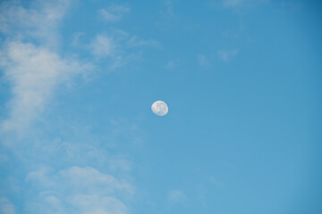 Partial moon in blue sky with clouds