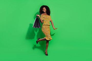 Full length photo of cheerful dark skin girl hold bags wear stilettos have good mood isolated on...