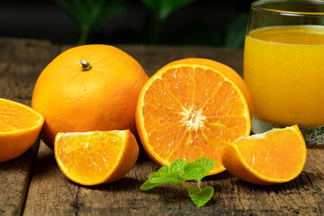 Close up orange fruit cut in half with slice orange and a glass of orange juice on the wooden table.