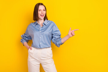 Photo of sweet adorable young woman wear blue shirt smiling winking pointing finger empty space...