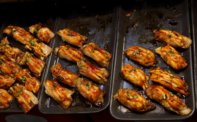 Bacon grilled and mayonnaise on top sushi in row on black tray for sale in Thailand.