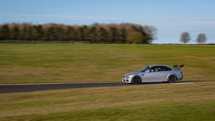 A panning shot of a racing car as it circuits a track.