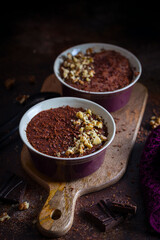 Cold cream, dessert, chocolate pudding with nuts and chocolate on the table, selective focus