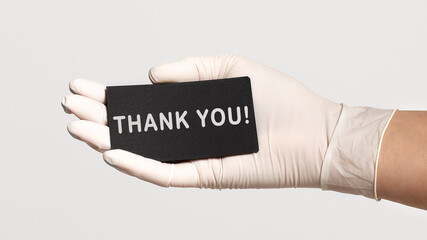 Closeup of the hand in a white sterile glove holding a card with text - Thank you