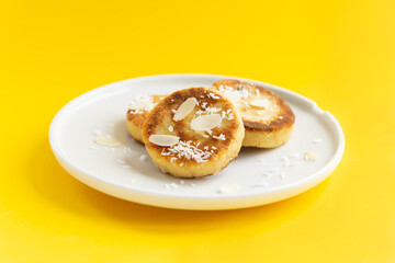 Tofu cheese pancakes on a plate on a yellow background. Vegan food, sugar, gluten and lactose free.
