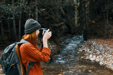 woman with a camera on nature in the mountains near the river side view