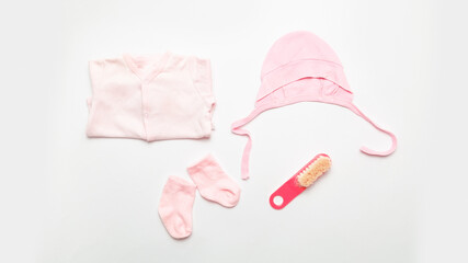 Motherhood concept. Pink clothes for a little girl with socks. Things for newborns. Baby accessories on white background. top view.