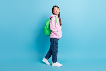 Fototapeta na wymiar Full length profile side photo of young girl happy smile rucksack go walk look empty space isolated over blue color background