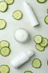 Obraz na płótnie Canvas Cosmetics and cucumber slices on white textured background