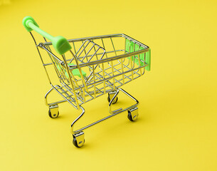 Empty supermarket shopping cart isolated on yellow background. The concept of buying and selling...
