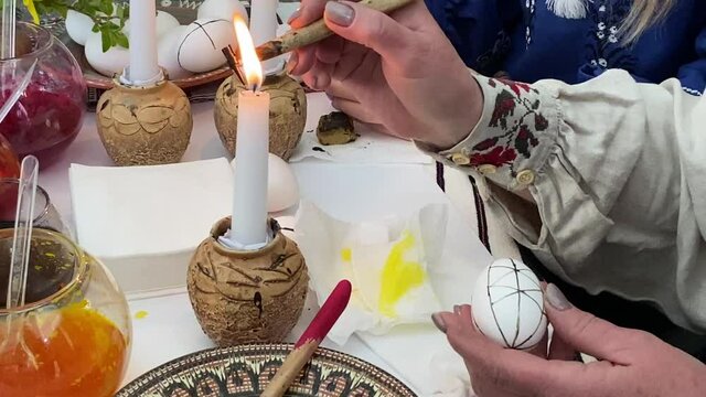 Easter egg Ukrainian painting and decorating activity concept: Human hands painting Easter eggs. Female craftman hands painting easter egg Ukraine traditonal folk process creating with the wax