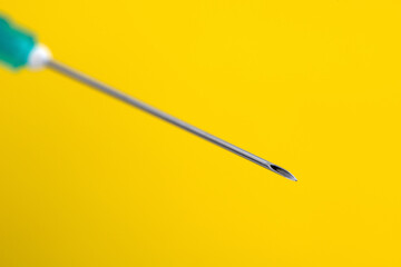 Medical syringe needle on a yellow background.