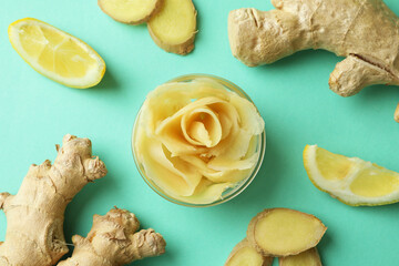 Bowl with pickled ginger, lemon and ginger on mint background