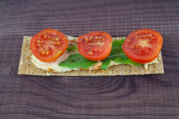 A crispy snack with fresh tomatoes and arugula. Healthy natural snack
