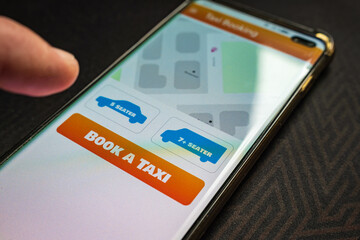 Male thumb finger over book taxi app button smartphone screen