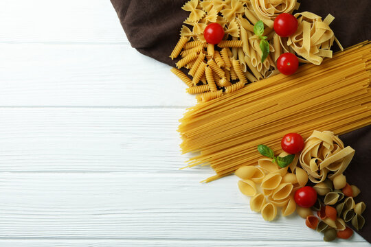 Uncooked pasta on kitchen towel on white wooden background - Powered by Adobe