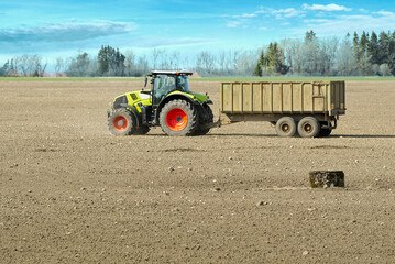 Fototapeta premium Spring work at farm. Farmer in tractor preparing the field for sowing. Farmer land and traktor. Sowing is spring time agricultural activities