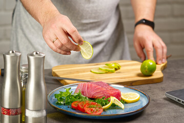 Cooking with notebook tuna steak in home kitchen. Online cooking recipe concept, fish cooking at home. lifestyle, healthy eating, cooking and dieting concept.