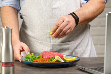 Cooking with notebook tuna steak in home kitchen. Online cooking recipe concept, fish cooking at home. lifestyle, healthy eating, cooking and dieting concept.