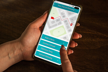 Male thumb finger over parcel delivery app on smartphone screen