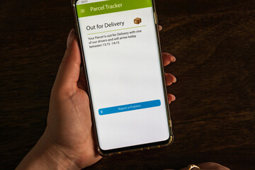 Male thumb finger over parcel delivery app on smartphone screen