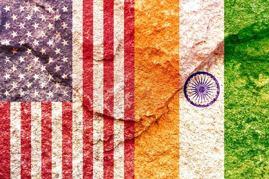 USA and India vertical national flags together on weathered rock wall background, abstract US India international politics relationship partnership concept