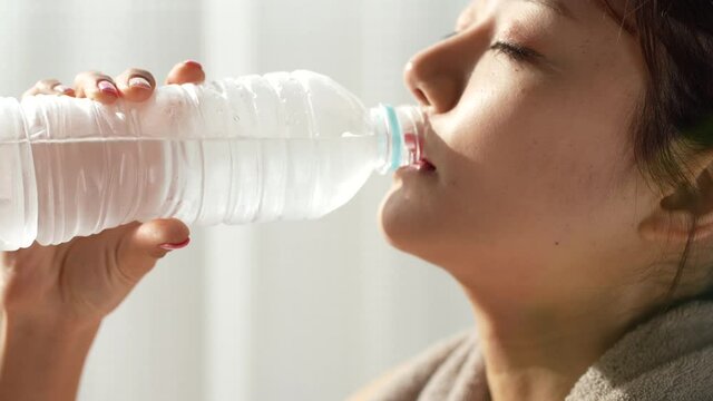 水を飲むスポーツウェアの若い女性