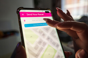 Male thumb finger over parcel delivery app on smartphone screen