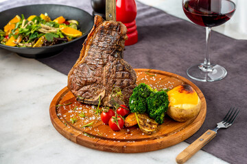 Medium rare Grilled T-Bone Steak with potato wedges, broccoli and wine on serving board block on...