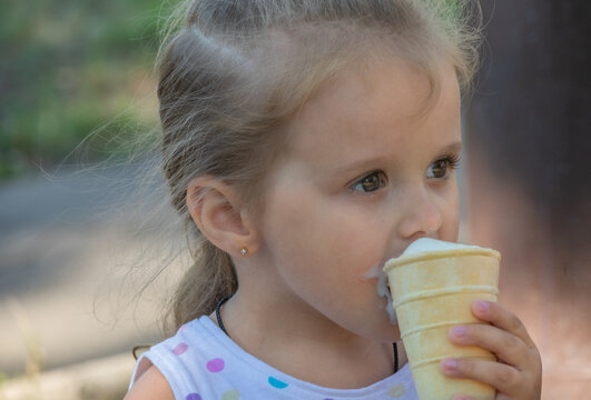 portrait, little girl 3 years old with huge eyes, eating ice cream in a waffle cup in the park