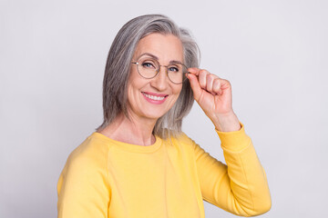 Photo of mature cool smiling cheerful positive woman in glasses wear yellow sweater isolated on grey color background