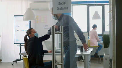 Caucasian male greeting his collegue with elbow to avoid covid19 infection. Workers working in new normal company office keeping social distancing during coronavirus global pandemic
