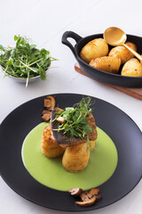 Rainbow trout, Oncorhynchus mykiss with skin, green pea puree, baked new potatoes and creamy mushrooms embellished with young fresh pea plants